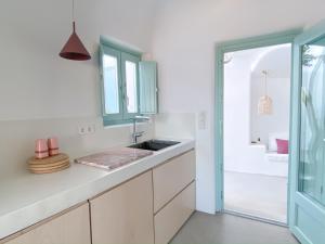 una cucina bianca con lavandino e finestra di Vima Santorini, Traditional Luxury a Emporio
