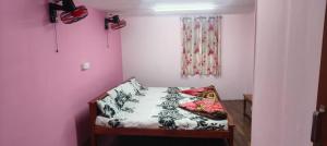 a small bed in a room with a pink wall at Bharath Homestay in Vālpārai