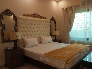 a bedroom with a large bed with a large headboard at Hotel Luxe Heights Lahore in Lahore