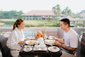 Um homem e uma mulher sentados à mesa a comer. em The Suites At Mount Malarayat em Lipa