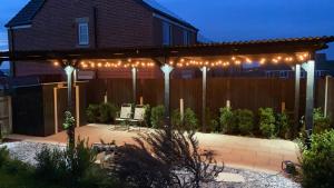 a backyard with a pergola with lights on it at Music lovers house in Morley