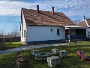 een wit huis met een stapel stenen ervoor bij Róza Vendégház in Kiskunhalas