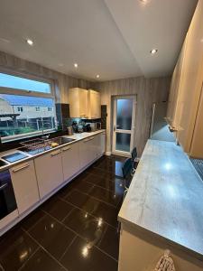 uma cozinha com armários brancos e uma grande janela em Music lovers house em Morley