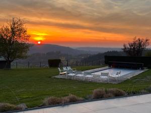 um grupo de cadeiras sentadas em torno de uma piscina ao pôr do sol em Oneux Village em Theux