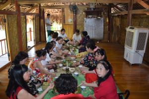 Un gruppo di persone seduti intorno a un tavolo che mangiano cibo di Homestay Long Coc a Phú Thọ