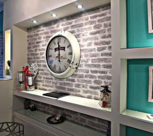 a clock on a brick wall with a shelf at Home Sweet Home! in Volos