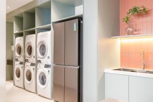 a laundry room with three washes and a refrigerator at M Village Kỳ Đồng in Ho Chi Minh City