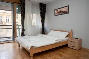 - une chambre avec un lit doté de draps blancs et une fenêtre dans l'établissement Tommy Apartment, à Belgrade