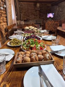 una larga mesa de madera con platos de comida. en Old House, en Ushguli