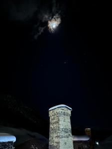 einen Uhrturm mit dem Mond am Himmel in der Unterkunft Old House in Uschguli