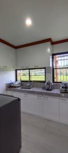 a large kitchen with white counters and windows at CASA VICTORIA PENSION HOUSE TANDAG CITY -Vassilis in Somosomo