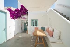 Camera bianca con divano bianco e fiori viola di Vima Santorini, Traditional Luxury a Emporio