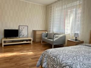 Schlafzimmer mit einem Bett, einem TV und einem Stuhl in der Unterkunft Imantas apartment in Daugavpils