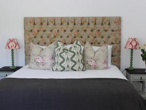 ein Schlafzimmer mit einem Bett mit Kissen und einem Kopfteil in der Unterkunft Le Petit Paris in Franschhoek