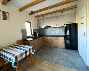 a kitchen with white cabinets and a black refrigerator at Winnica Sielskie Kresy in Michałowo