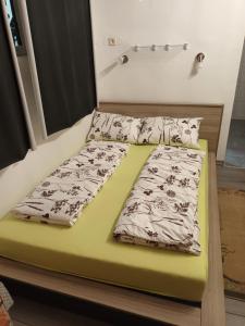 a bed with two sheets and pillows on it at Studio apartman Kamenčić in Osijek