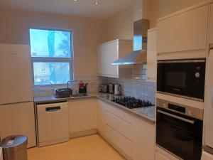 a kitchen with white cabinets and a window at London Luxury 2 bedroom flat 4 mins to Ilford Stn Sleeps x8 Free Parking in Ilford