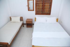 een kamer met 2 bedden en een spiegel bij Rose Fort Homestay in Jaffna