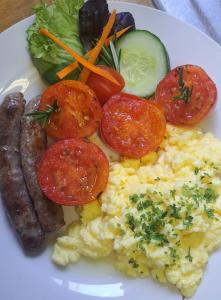 un plato de desayuno con huevos, salchichas y tomates en Haus Müller en Clanwilliam