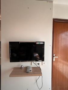 een flatscreen-tv aan een muur met afstandsbediening bij Crystal box NIMBUS Noida expressway in Noida