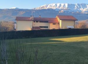 ein Haus auf einem Feld mit einem Berg im Hintergrund in der Unterkunft Complesso turistico Aurora - camere B&B in Poggio Picenze