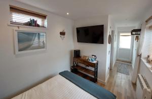 a bedroom with a bed and a flat screen tv at Beachcroft Beach Snug in Seaton