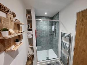 a shower in a bathroom with a glass shower stall at Beachcroft Beach Snug in Seaton