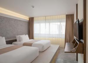 a hotel room with two beds and a flat screen tv at Nidhra Boutique in Bangkok