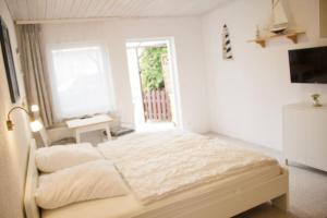 a white bedroom with a bed and a window at schöner Gartenbungalow (Nr. 2) mit Terrasse - Strandvogtei Sellin in Ostseebad Sellin