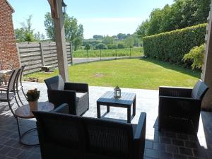 eine Terrasse mit Stühlen, einem Tisch und einer Liegewiese in der Unterkunft DE LANDSHOEVE vakantiewoningen in Zwalm