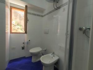 a bathroom with a toilet and a sink and a window at Casa Centurioni in Isola del Giglio