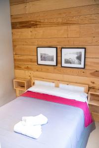 1 dormitorio con 1 cama con 2 cuadros en la pared en Carving Surf Hostel, en San Esteban de Pravia