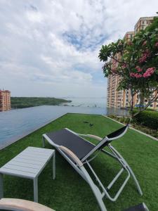 a chair and a table on a lawn with a view of the water at Seaview Infinity Retreat Urban Suite 3R2B 8Pax Georgetown in Jelutong