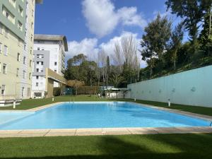 ein großer Pool in einem Hof neben einem Gebäude in der Unterkunft Apart T3 com piscina tenis ginasio e parq infant in Lissabon