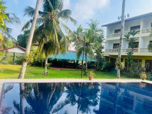 una piscina frente a una casa con palmeras en Muthumuni Ayurveda River Resort en Aluthgama