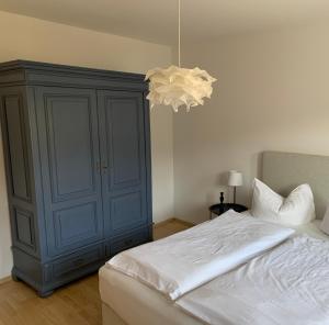 a bedroom with a bed with a blue cabinet and a chandelier at Ferienwohnung Geißler in Radebeul