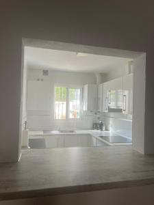 een keuken met witte kasten en een groot raam bij Casa Pom at the Beach in Torre de Benagalbón +30 foto's