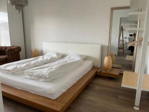 a bed with white sheets and a mirror in a room at goodstay in Winterthur