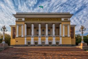 a yellow building with a flag on top of it at Nadezhda Apartment on Abay Avenue 59 in Almaty