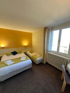 a hotel room with two beds and a window at Logis Hôtels - Hôtel et Restaurant Le Lion d'Or in Gramat