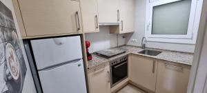 a small kitchen with a refrigerator and a sink at VIDA BRAVA, S´agaro garden loft in S'Agaro