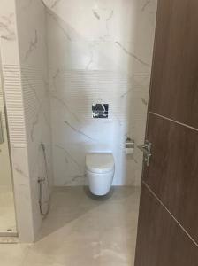 a white bathroom with a toilet and a shower at Résidence Tilel 2 à Chatt Mariem in Sousse