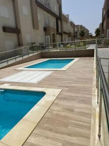 two swimming pools in front of a building at Résidence Tilel 2 à Chatt Mariem in Sousse