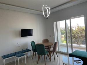 a living room with a table and chairs and a tv at Résidence Tilel 2 à Chatt Mariem in Sousse