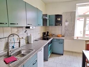 uma cozinha com armários azuis e um lavatório em Zur Pforte em Arnstadt