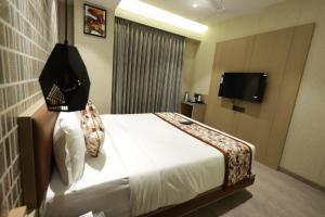 a hotel room with a bed and a flat screen tv at Hotel Sapphire 26 in Surat