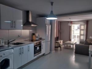 une cuisine avec des placards blancs et un salon dans l'établissement Apartamentos Palillero, à Cadix