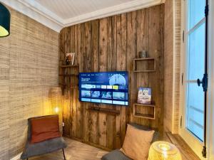 a living room with a tv on a wooden wall at Rouen Hypercentre - Le relais des Amis in Rouen