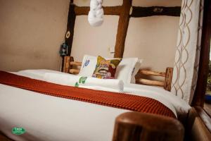 Bett mit weißer Bettwäsche und Kissen in einem Zimmer in der Unterkunft Sipi Falls Cottages in Sipi