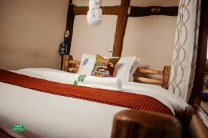 a bed with white sheets and pillows in a room at Sipi Falls Lodge in Sipi